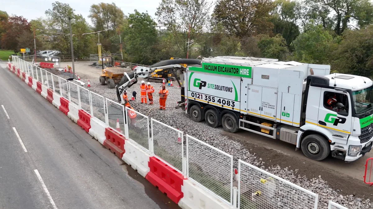 A Green Power vacuum excavation lorry at work beside a road at Hathern, its crew in orange