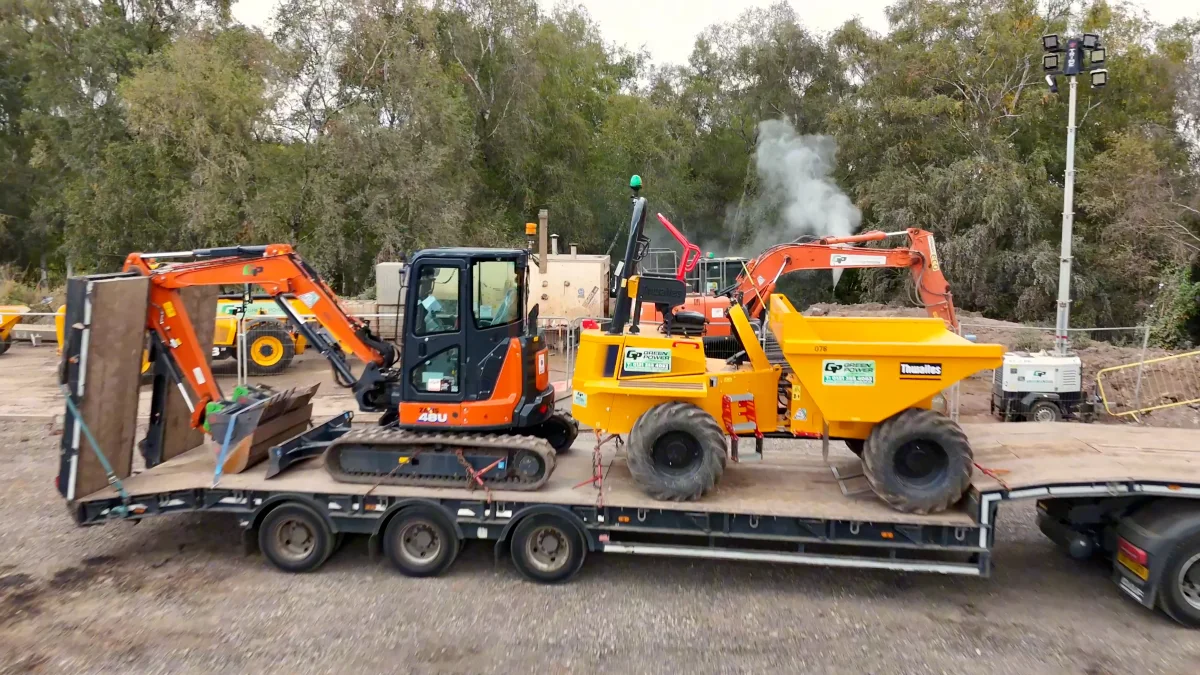 A low-loader carrying a digger and a dumper in the Green Power yard